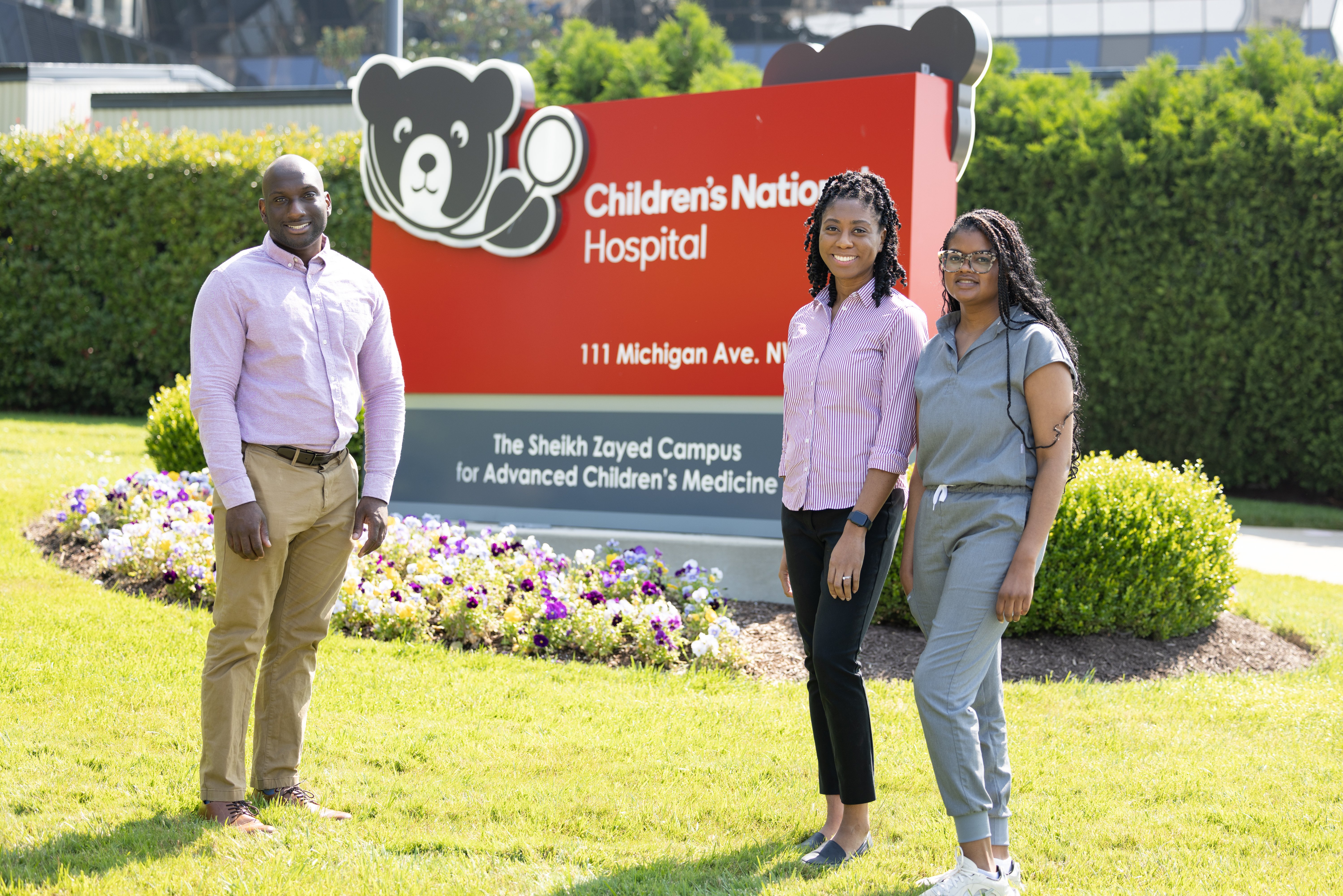 The people stand in front of a sign outside of Children's National Hospital.